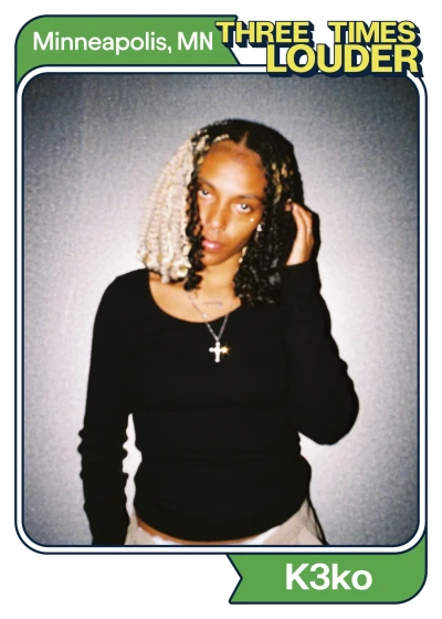 Young woman with curly braided hair, wearing a black top and cross necklace, posing against a gray background with a "Three Times Louder" logo and "Minneapolis, MN" text.
