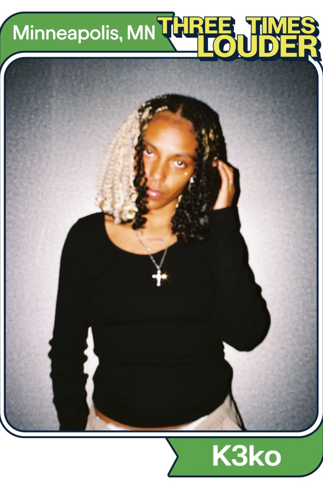 Young woman with curly braided hair, wearing a black top and cross necklace, posing against a gray background with a "Three Times Louder" logo and "Minneapolis, MN" text.