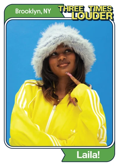 Smiling young woman in a bright yellow jacket and fluffy white winter hood, posing against a blue background with a "Three Times Louder" logo and "Brooklyn, NY" text.
