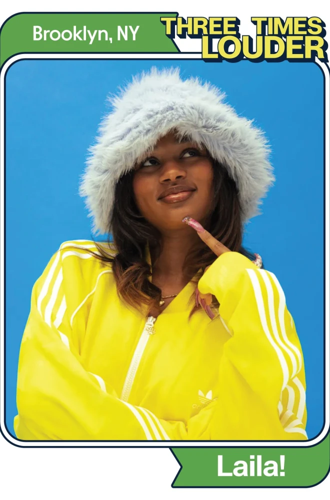 Smiling young woman in a bright yellow jacket and fluffy white winter hood, posing against a blue background with a "Three Times Louder" logo and "Brooklyn, NY" text.